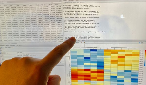 finger pointing to computer screen with data spreadsheet running RStudio cloud program.